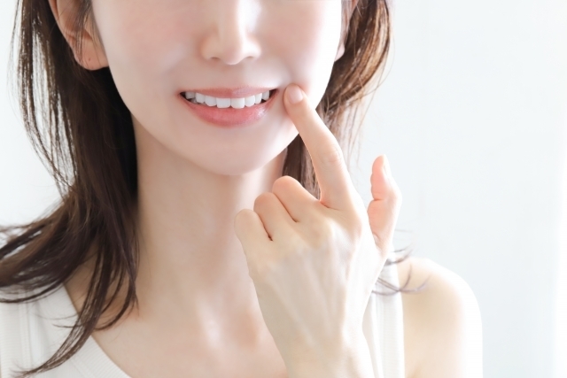 女性が自身の白い歯を見せて指差している様子