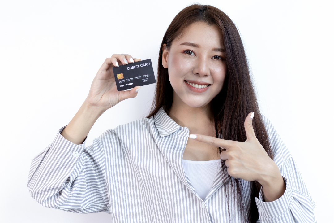 クレジットカードを手に持ち、指さす日本人女性