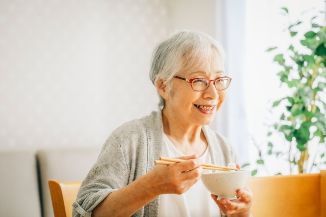 自然な笑顔で食事をする高齢者女性