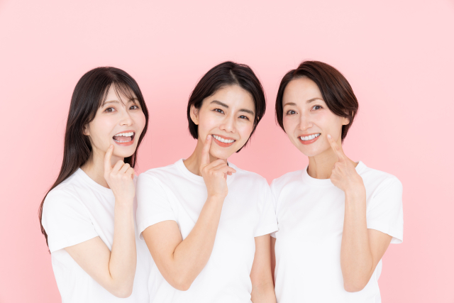 歯を指さして微笑む女性たち