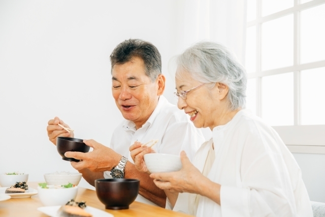 笑顔で家族と食事をする高齢者女性