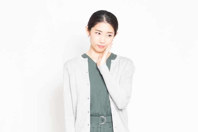 頬に手を当て悩む女性